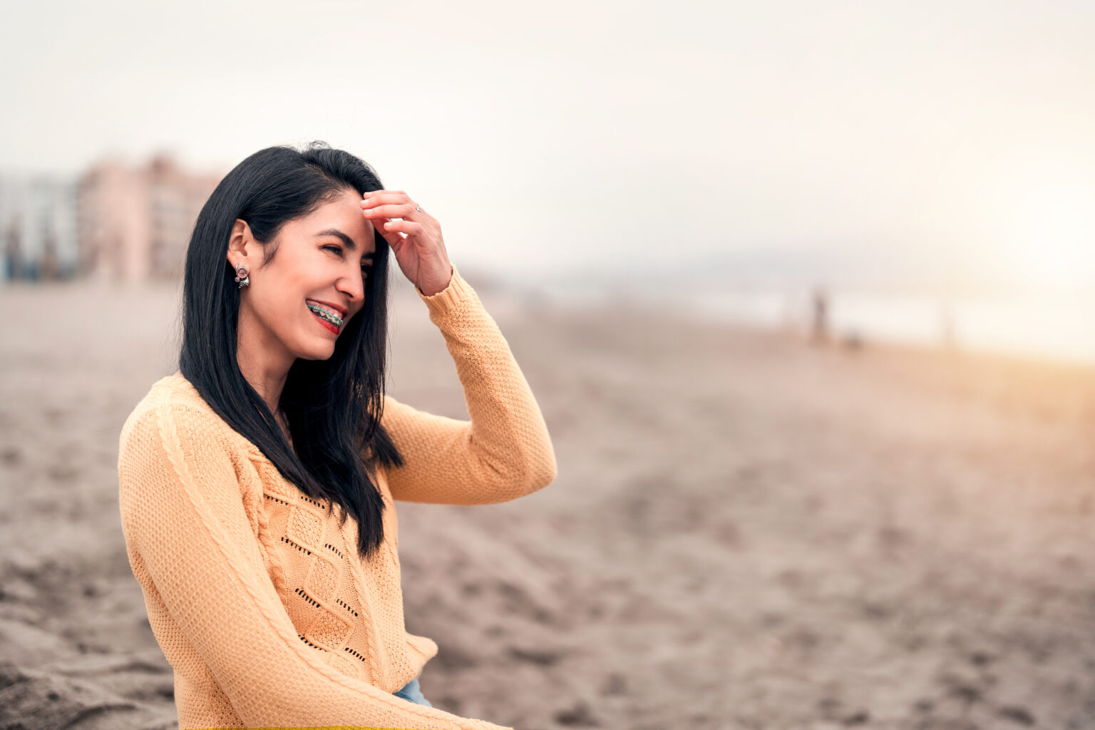 young latin woman with braces laughing on the beach portrait