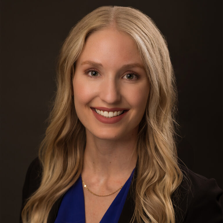 Orthodontist Dr. Brooke E. Brown smiling in business attire and a sleek gold necklace